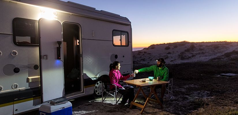 Zwei Camper sitzen vor ihrem Wohnwagen