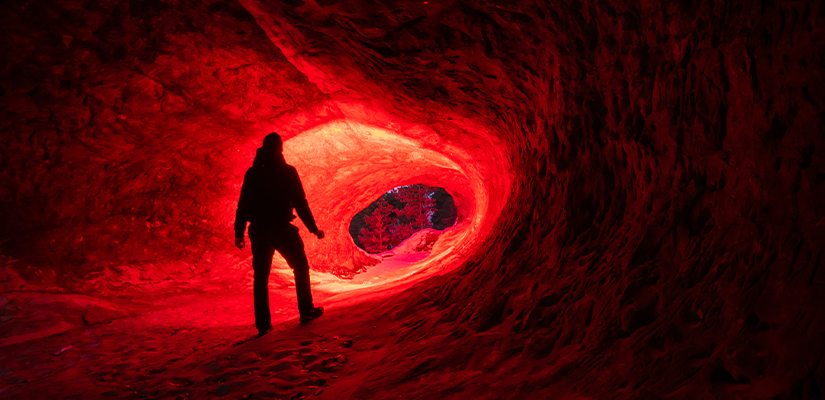 Man mit Rotlicht Taschenlampe in einer Höhle