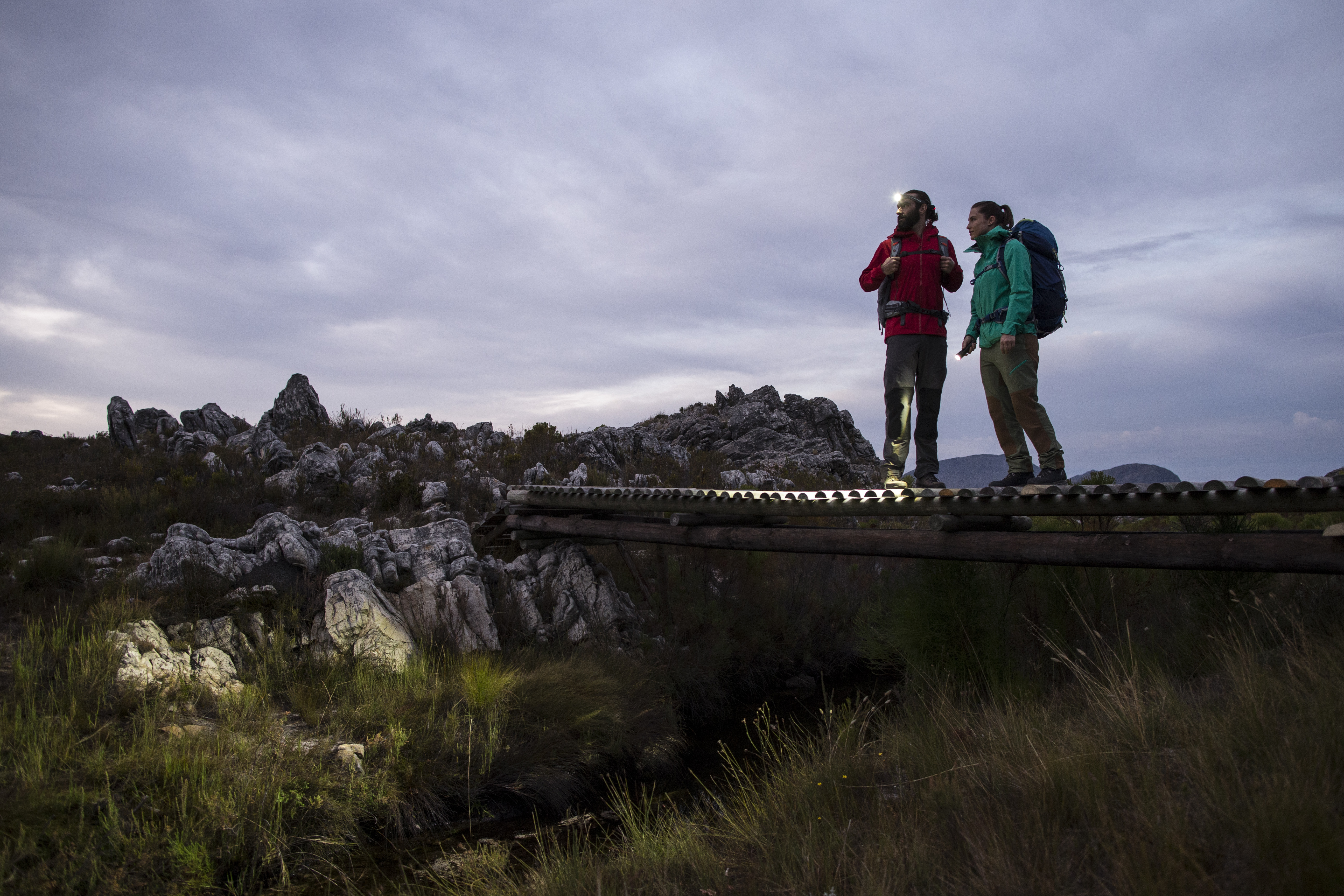 A woman and a man are hiking and using headlamps