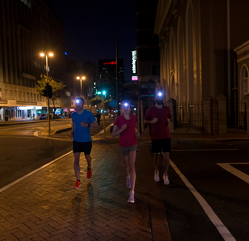 Drei Jgger mit Stirnlampen laufen durch die Stadt