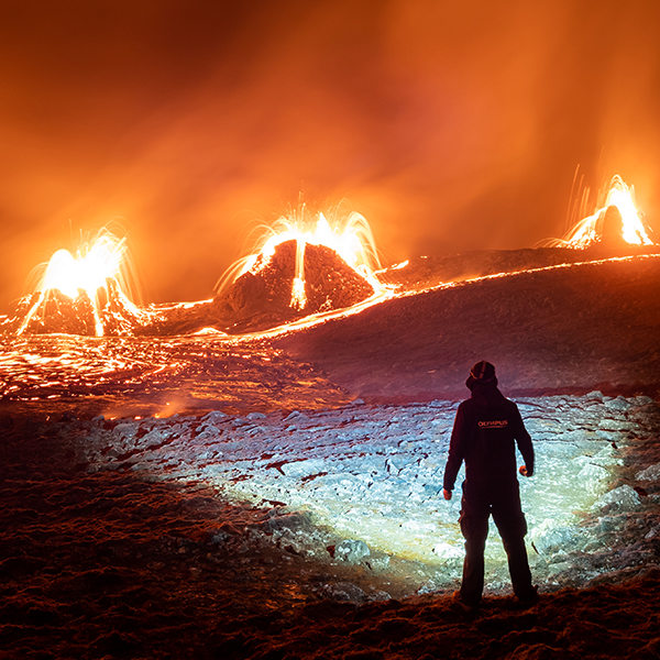 Man with a very bright flashlight infront of three volcanos