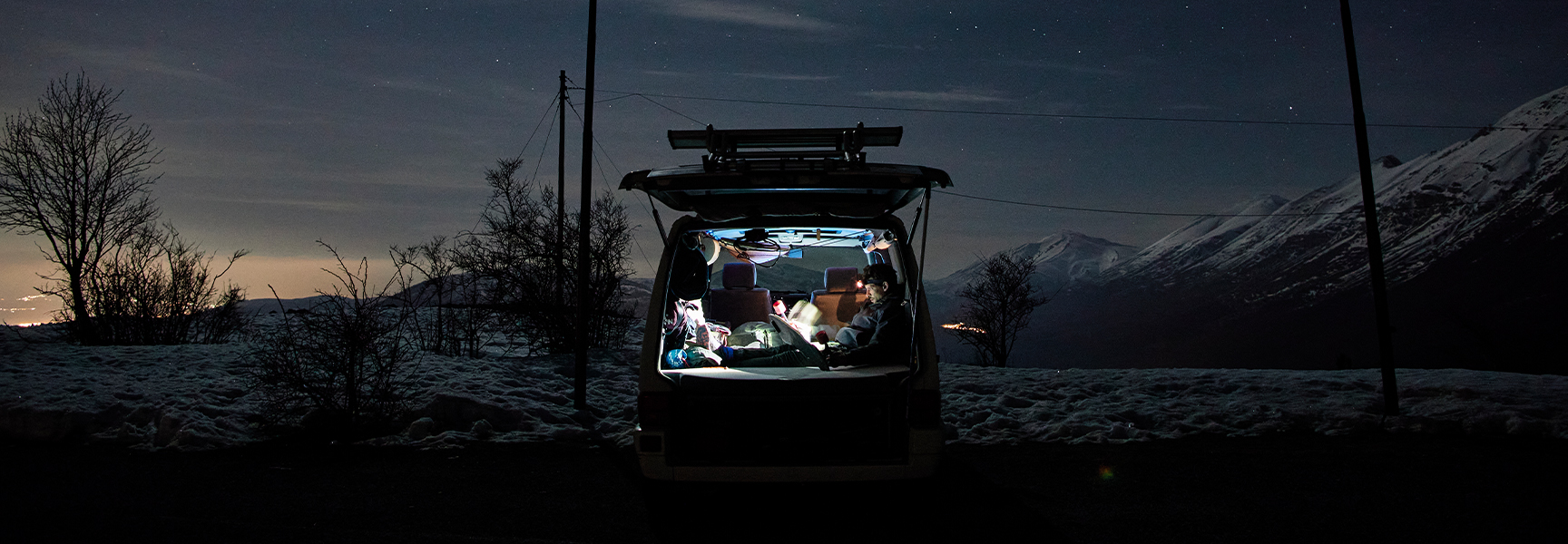 Personen sitzen im Auto und verwenden Campinglampen