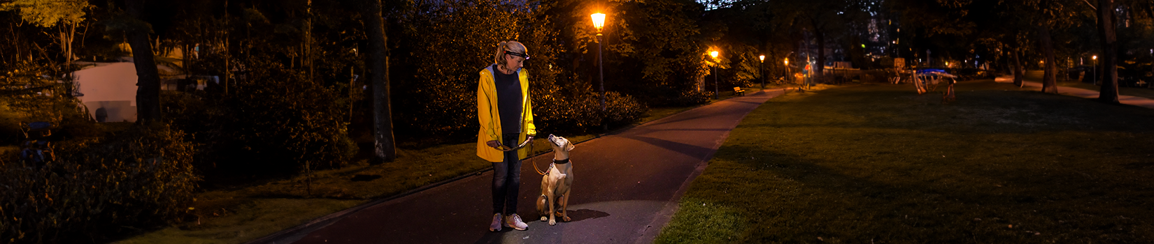 A woman with a headlamp takes her dog for a walk in the dark