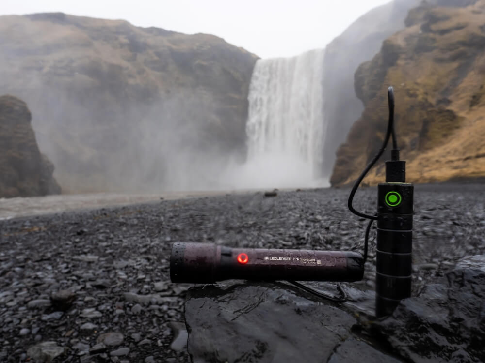 Eine Powerbank und eine Taschenlampe vor einem Wasserfall
