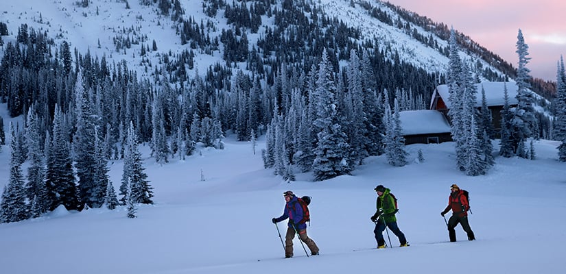 Drei Skifahrer machen eine Tour mit Stirnlampen