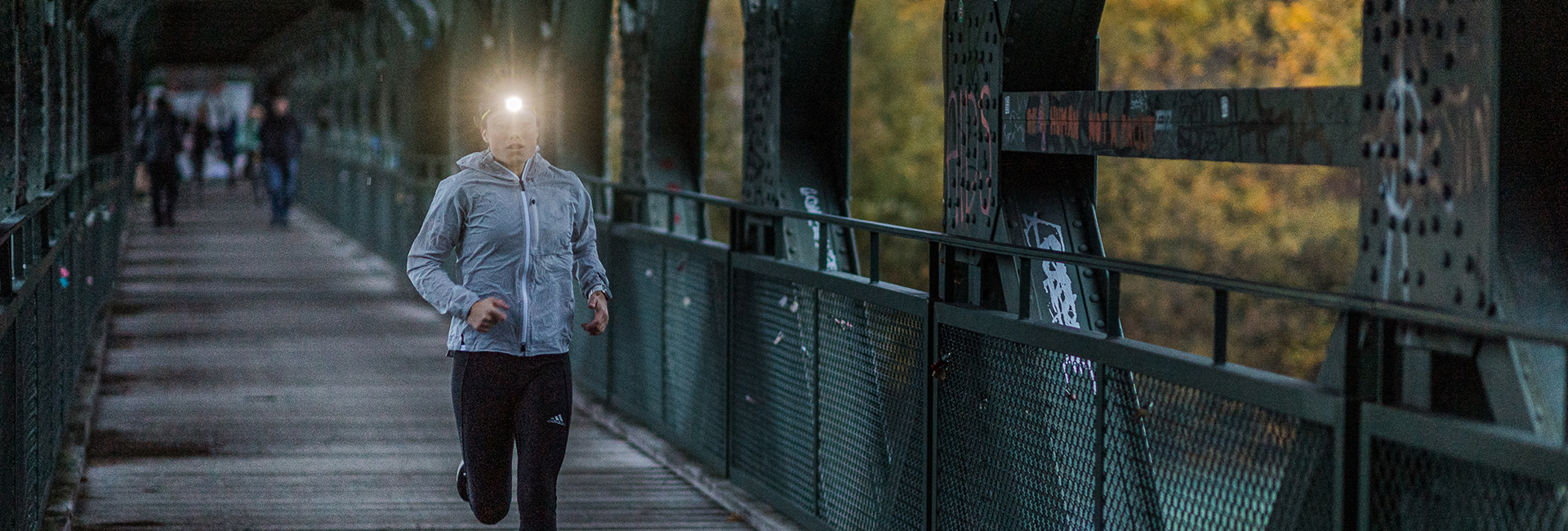 A woman is jogging in the dark and is using a headlamp