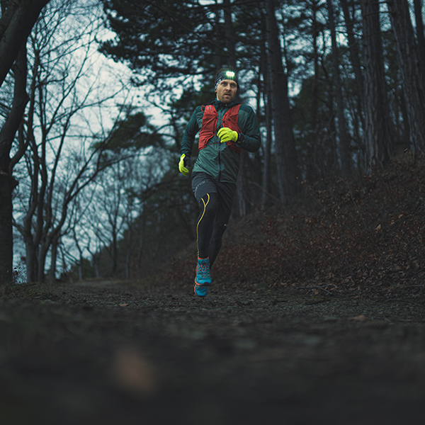 Das Bild zeigt einen Trailrunner mit Stirnlampe