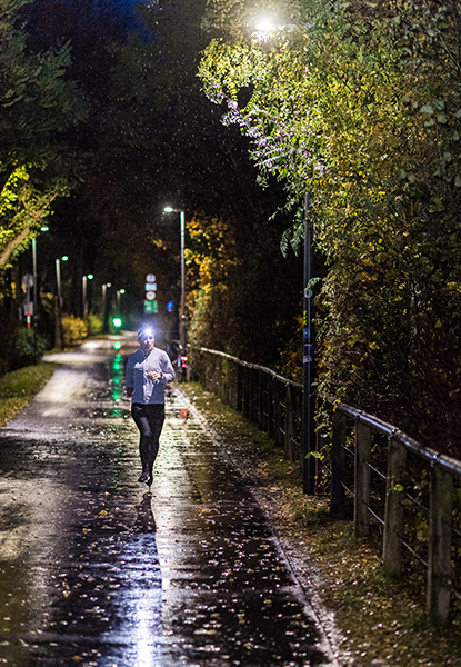 Eine Frau mit Stirnlampe läuft durch den Regen