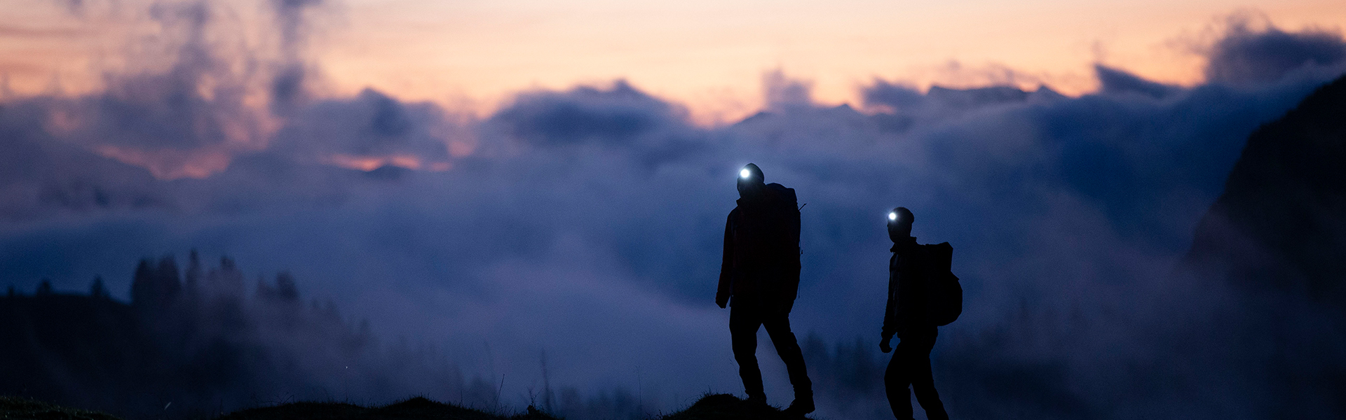 Das Bild zeigt zwei Trailrunner mit Stirnlampen