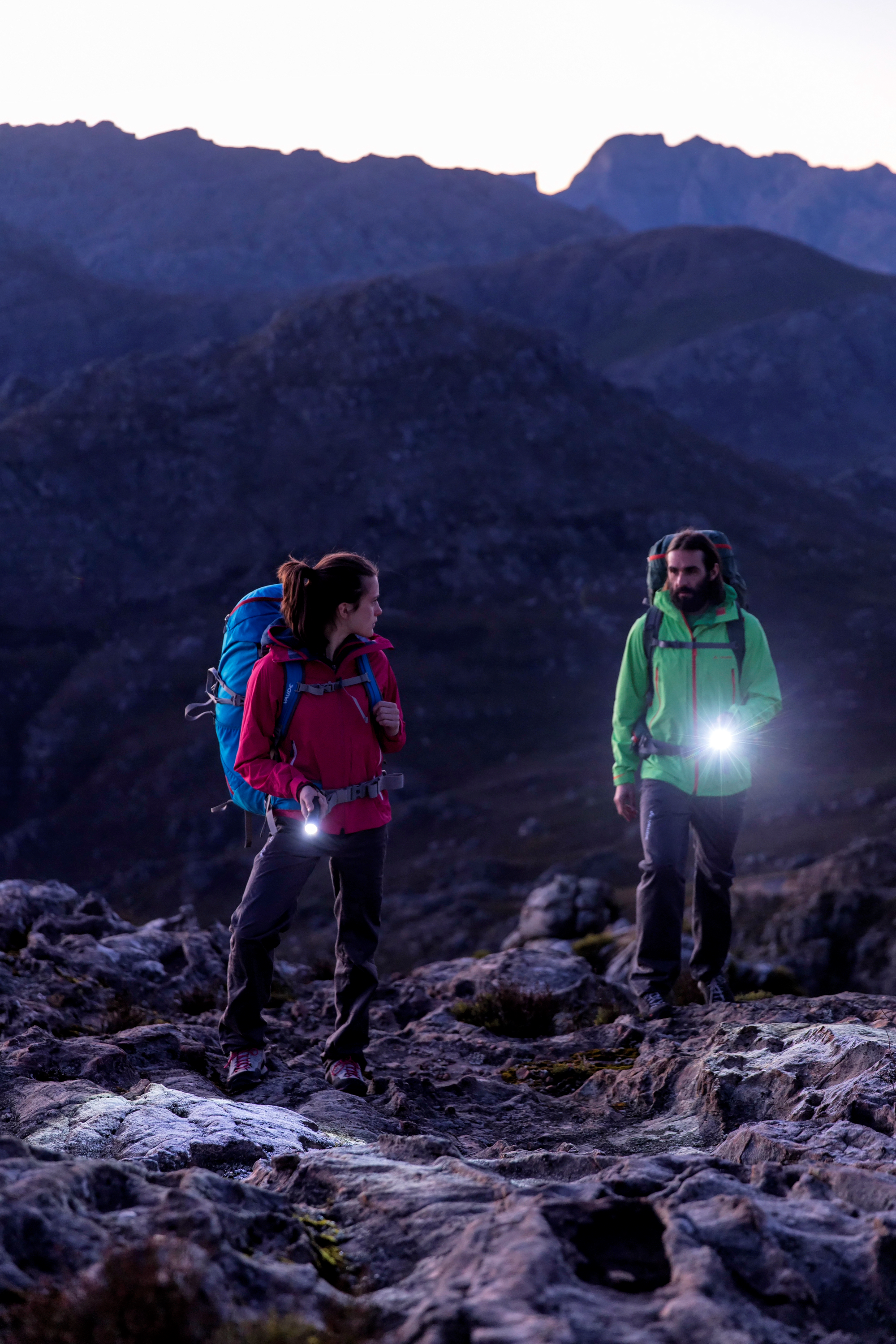A woman and a man with flashlights hiking