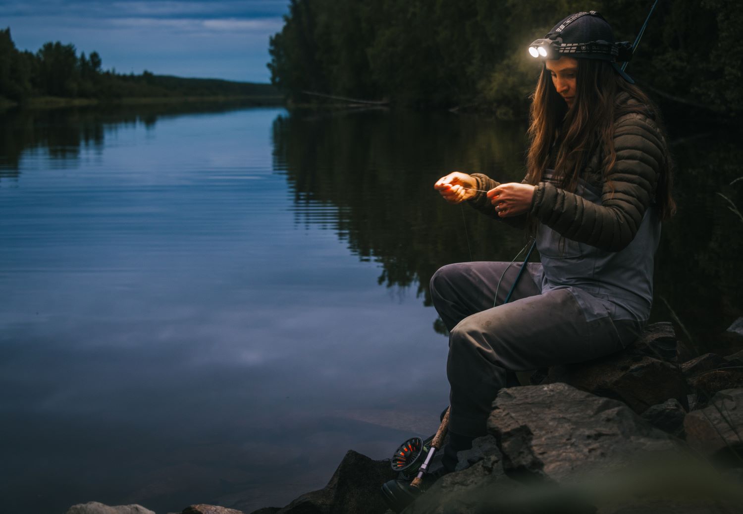 A woman uses a headlamp while fishing