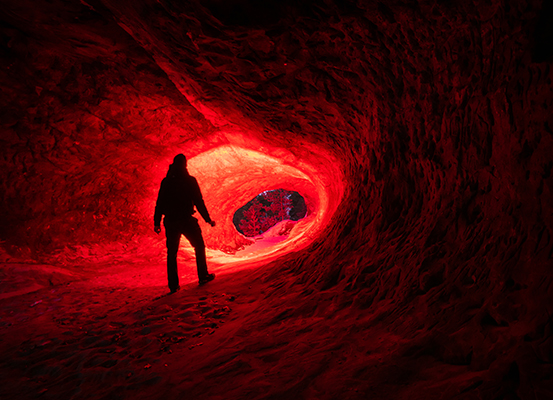 Person mit Rotlicht Taschenlampe in einer Höhle