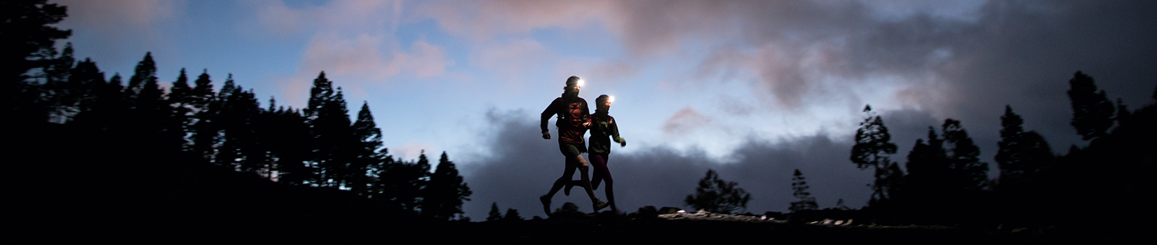 Two runners with headlamps in the dark
