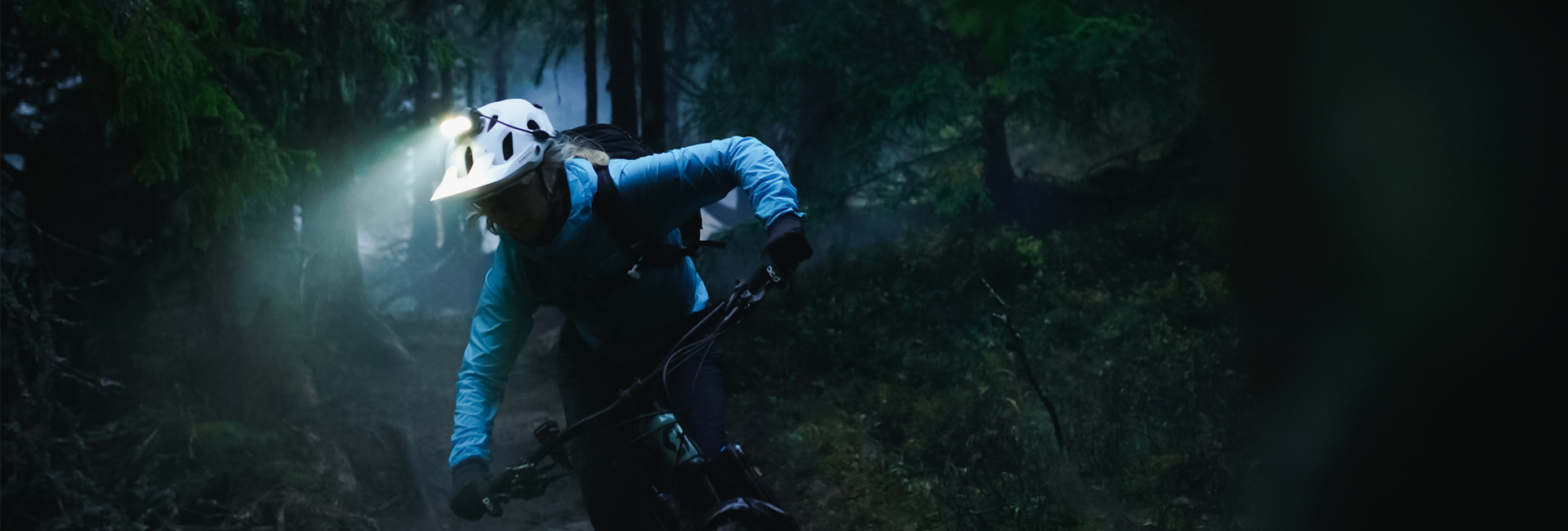 Ein Mountainbiker mit Helmlampe im Wald